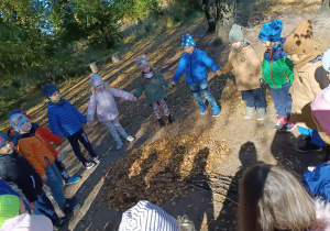 Dzieci stoją w kole na leśnej polance