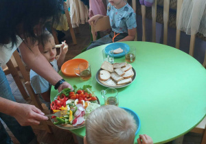 Pani pomaga dziecko wybrać warzywa na kanapkę