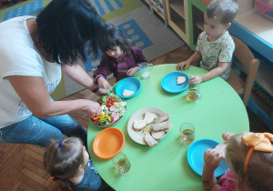 Pani pomaga dziecko wybrać warzywa na kanapkę