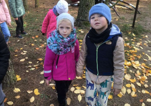 Dzieci stoją na tle wielkiej figury pająka