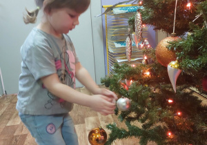 Dziewczynka wiesza bombkę na choince
