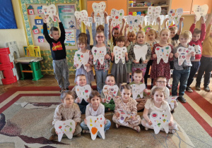 Dzieci pozują do zdjęcia, trzymają wykonane przez siebie prace plastyczne