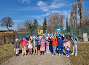 Przedszkolaki trzymają ręce w górze, pokazując niebieskie rękawiczki do zbierania śmieci