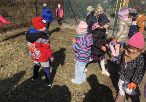 Pani trzyma worek na śmieci. Dzieci wrzucają do niego zebrane śmieci