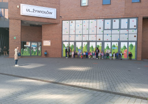 Dzieci stoją pod napisem „Ul. Żywiołów"
