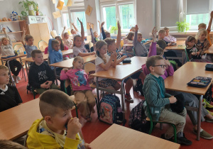 Dzieci siedzą w ławkach szkolnych