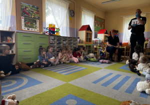 Pan pokazuje dzieciom numer alarmowy