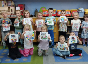 Przedszkolaki pokazują prace z napisem „Dzień Kropki”.