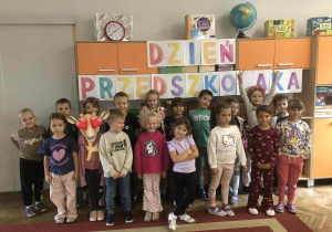 Dzieci stoją pod napisem „Dzień Przedszkolaka"