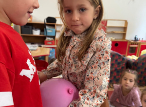 Dzieci trzymają się za ręce, między sobą mają balon