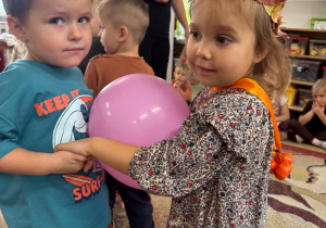 Dzieci trzymają się za ręce, między sobą mają balon