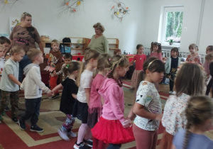 Dzieci trzymają się za ręce, idą po kole