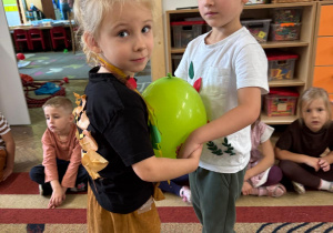 Dzieci trzymają się za ręce, między sobą mają balon