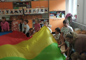 Dzieci z nauczycielką bawią się chustą animacyjną