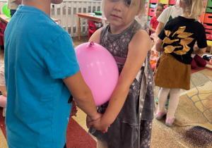 Dzieci trzymają się za ręce, między sobą mają balon