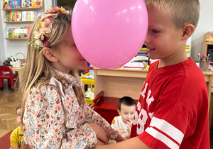 Dzieci trzymają się za ręce, między sobą mają balon