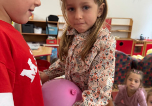 Dzieci trzymają się za ręce, między sobą mają balon