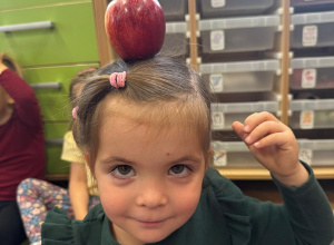 Dziewczynka ma na głowie jabłko