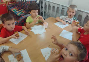 Dzieci siedzą przy stoliku i jedzą