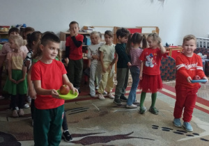 Chłopcy niosą jabłka na talerzykach