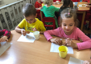 Dzieci siedzą przy stole i jedzą