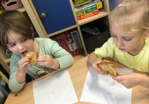 Dzieci siedzą przy stoliku i jedzą