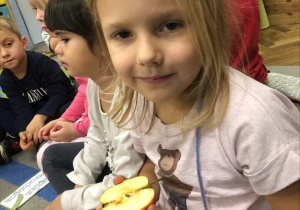 Dziewczynka trzyma połówkę jabłka