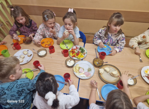 Dzieci siedzą przy stole, jedzą śniadanie