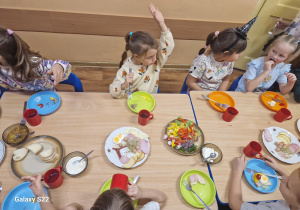 Dzieci siedzą przy stole, jedzą śniadanie