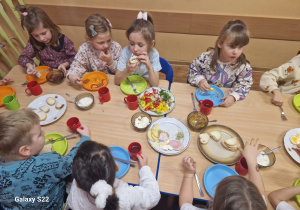 Dzieci siedzą przy stole, jedzą śniadanie