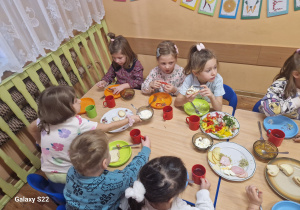 Dzieci siedzą przy stole, jedzą śniadanie