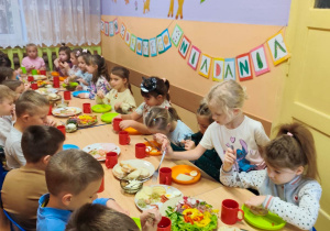 Dzieci siedzą przy stole, jedzą śniadanie