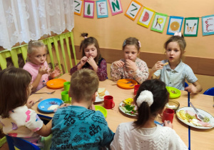 Dzieci siedzą przy stole, jedzą śniadanie