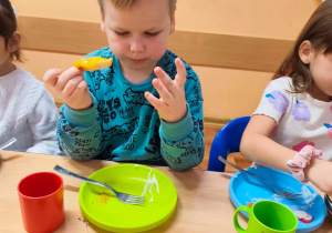 Dzieci siedzą przy stole, jedzą śniadanie