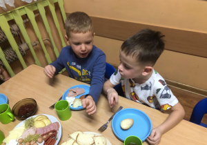 Dzieci siedzą przy stole, jedzą śniadanie