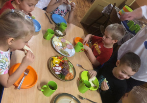 Dzieci siedzą przy stole, jedzą śniadanie