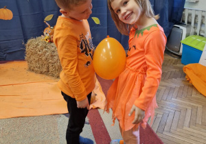 Chłopiec i dziewczyna mają miedzy sobą balon. Trzymają go brzuchami