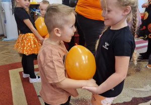 Chłopiec i dziewczyna mają miedzy sobą balon. Trzymają go brzuchami