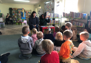 Dzieci siedzą na dywanie. Panie czytają opowiadanie