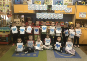 Dzieci trzymają kartki z niebieskimi sercami