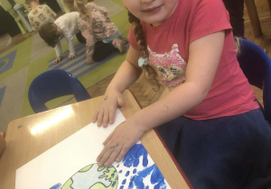 Dziewczyna odbija rękę na pracy plastycznej