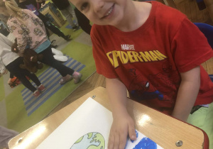 Chłopiec odbija rękę na pracy plastycznej