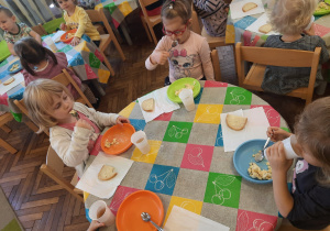 Dzieci jedzą przygotowaną przez siebie sałatkę jarzynową