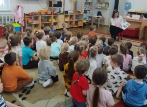 Dzieci siedzą na dywanie. Pani czyta opowiadanie.