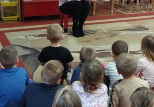 Dzieci siedzą na dywanie. Pani czyta opowiadanie.