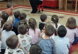 Dzieci siedzą na dywanie. Pani czyta opowiadanie.