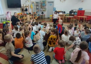 Dzieci siedzą na dywanie. Pani czyta opowiadanie.