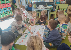 Dzieci oglądają ilustracje dinozaurów.
