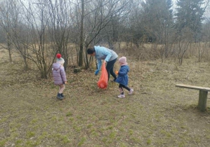 Nauczyciel z dziećmi sprząta okolicę.