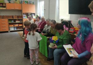 Dzieci wręczają upominki seniorom.